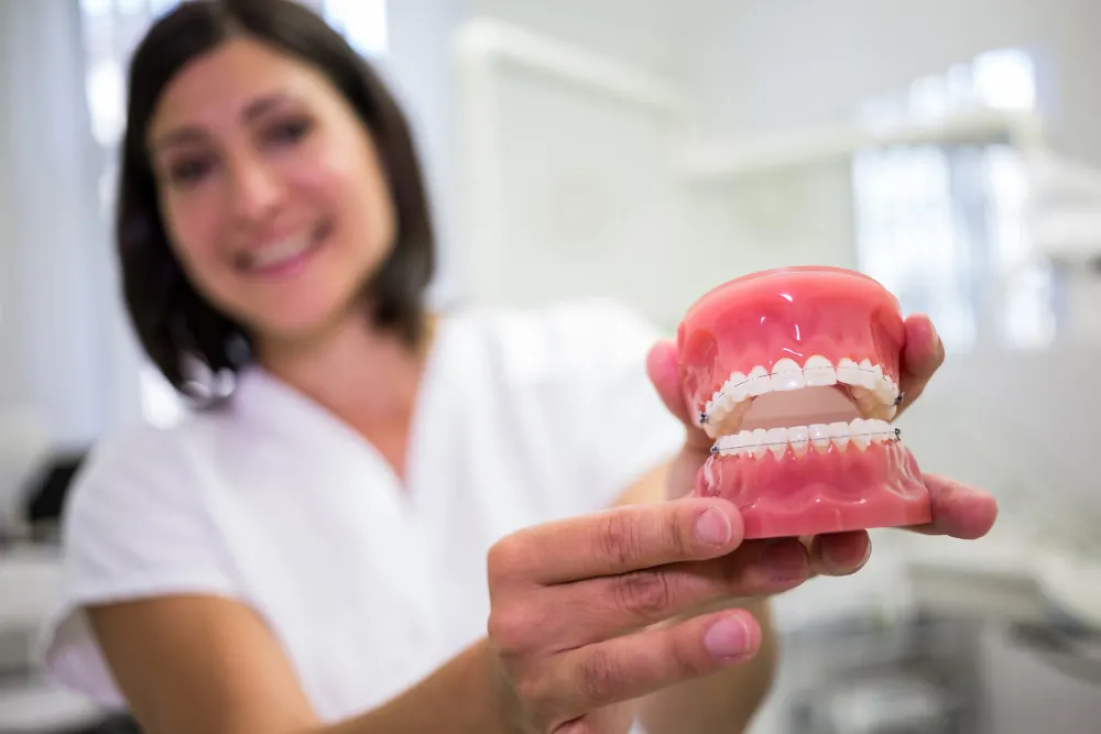 A dental professional holds up a denture model to show its fit and finish