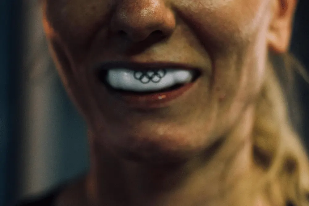 Close-up of a custom mouthguard printed with the Olympic rings, worn by an athlete