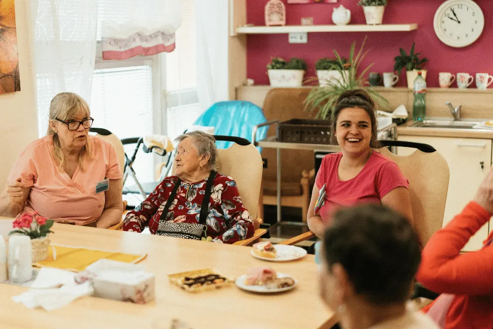 Aged care residents chatting and smiling with a carer around a table